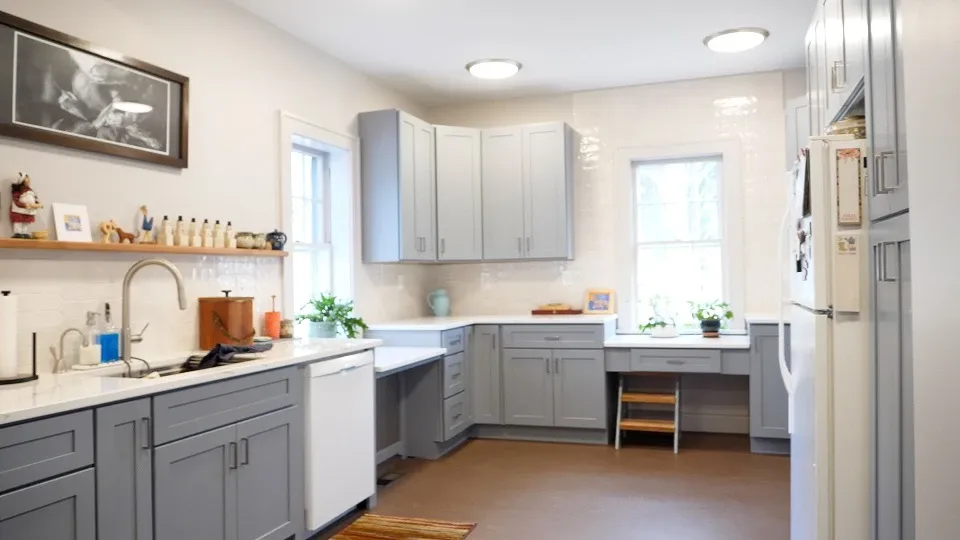 A white tiled kitchen with light gray cabinets.
