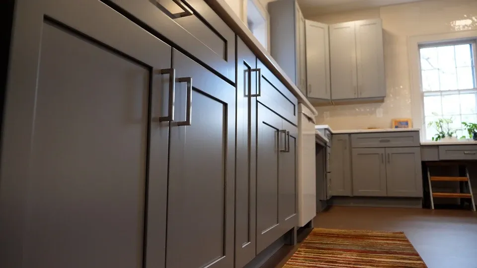 A floor-angled view of light gray cabinet doors. More cabinets are visible on the wall in the background.