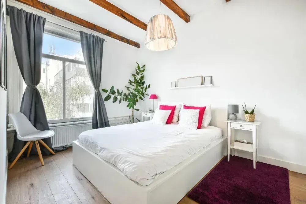 Updated bedroom interior featuring wood flooring, exposed ceiling beams, and modern finishes as part of a whole home remodel.