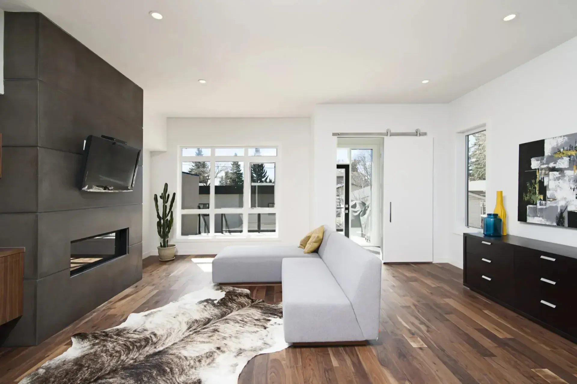 Open-concept home addition with hardwood flooring, modern fireplace, and large windows, showcasing custom remodeling and home expansion services.