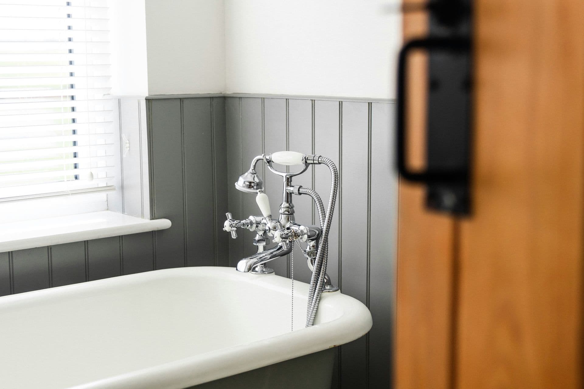 A beautifully updated bathroom featuring a classic clawfoot tub, chrome fixtures, and fresh wainscoting—blending historic charm with modern comfort.
