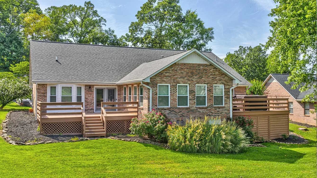 A red brick house with brown wood decks on the left and right sides.