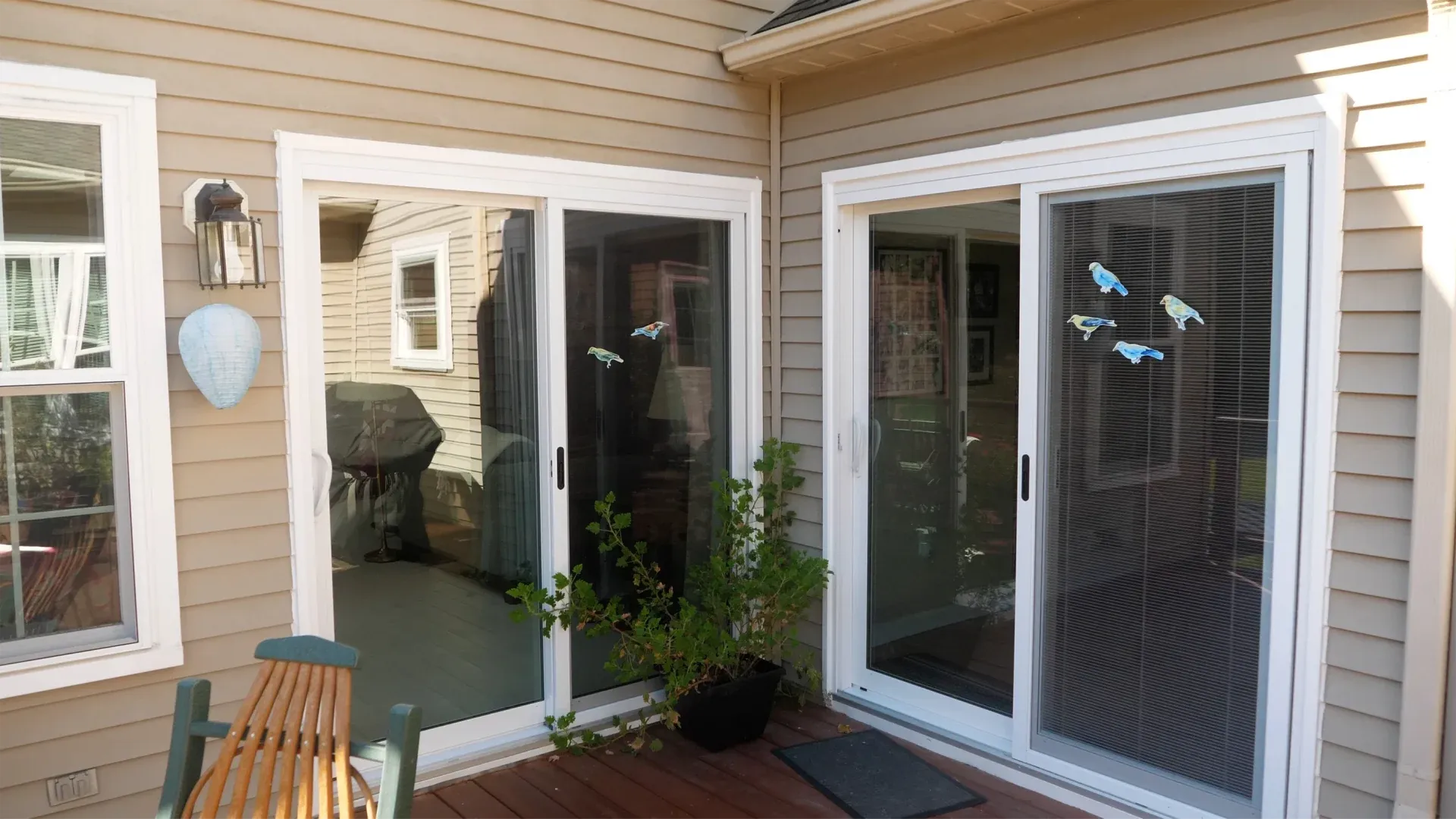 A photo of the corner of a deck with double glass sliding doors on either side.