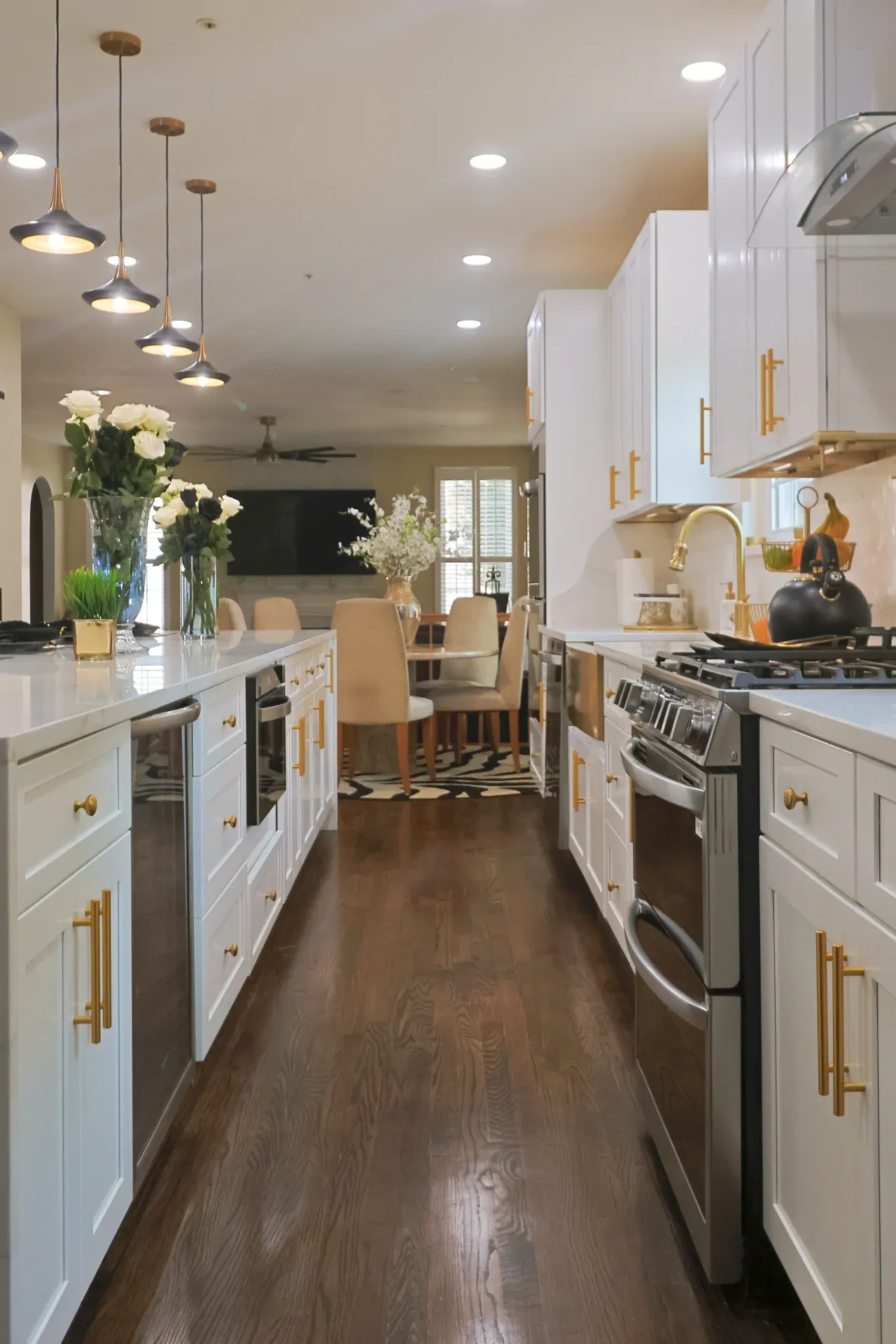 A view looking down the kitchen with the island on the left and the range on the right. A dining area is visible in the background.