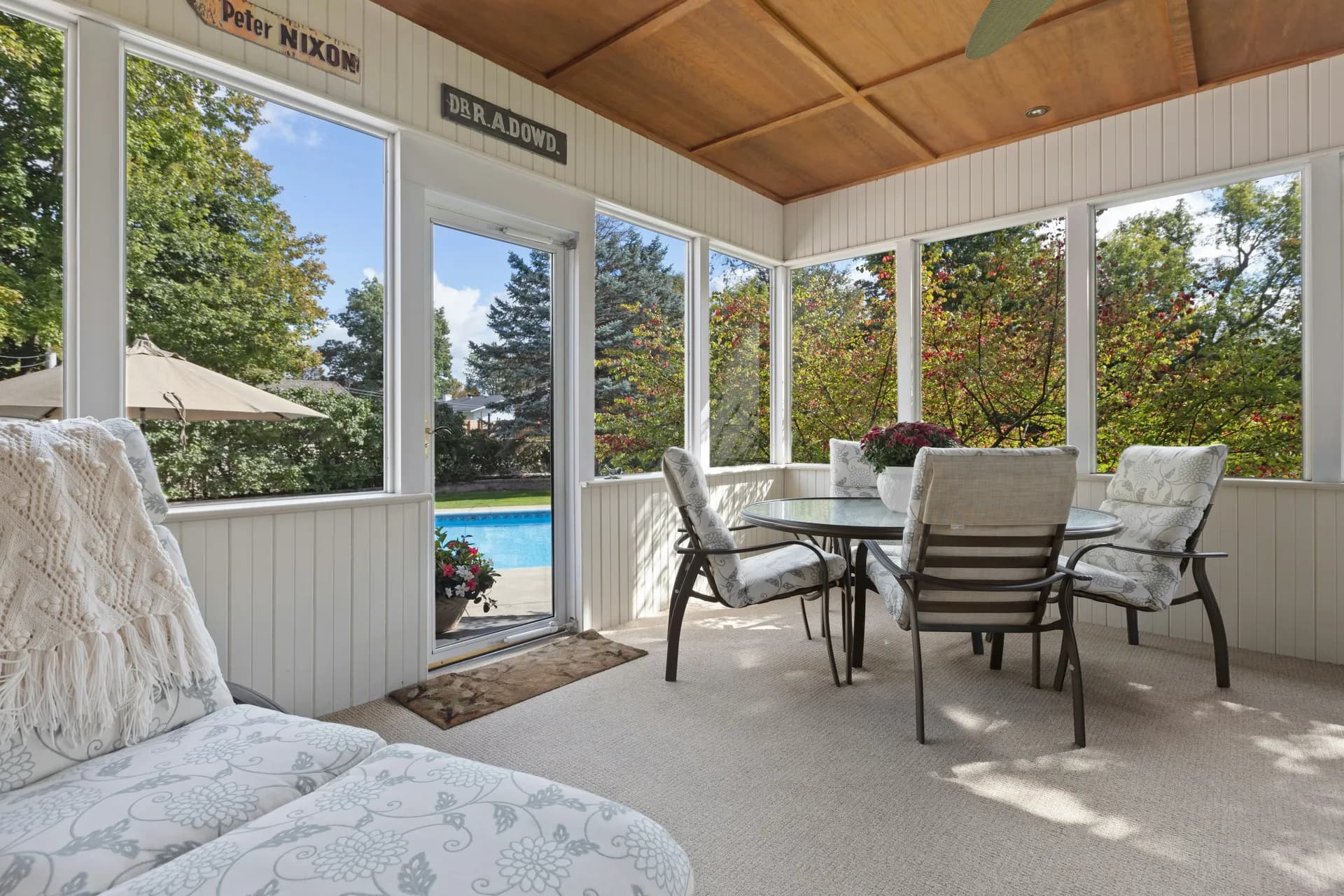 Bright four-season sunroom addition in a Maryland home with large windows, wood ceiling, and comfortable seating.