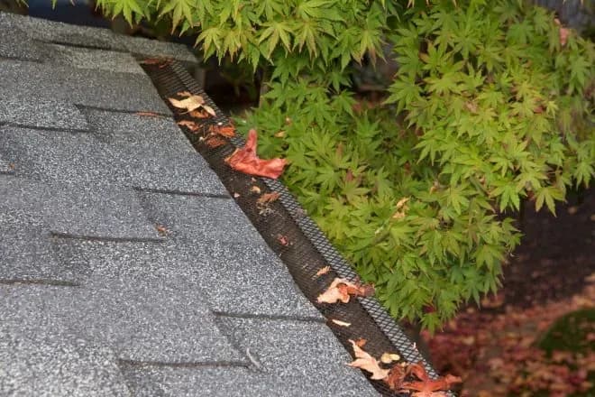 Plastic guard over new dark grey plastic rain gutter on asphalt - Integrity Home Pro