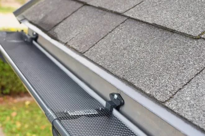 Plastic guard over new dark grey plastic rain gutter on asphalt - Integrity Home Pro