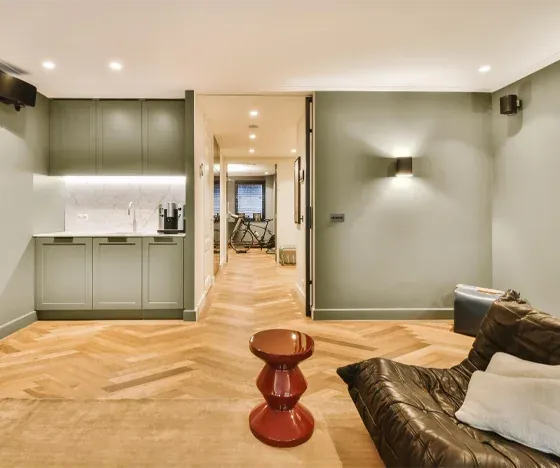 A basement living room with a kitchenette and a leather couch.