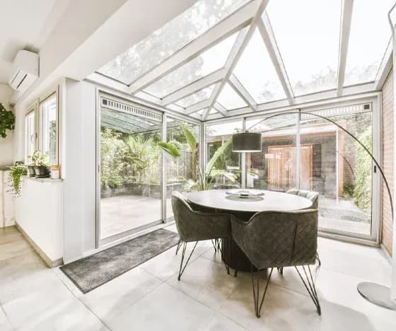 A glass sunroom addition with a dining table and chairs.