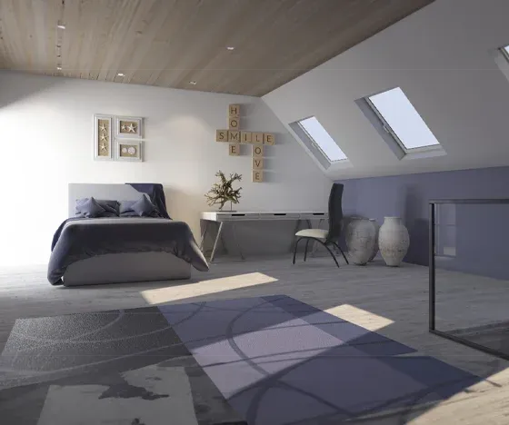 A finished attic room addition with a bed and a desk. Two skylights are on the far right wall.