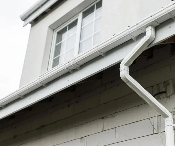 An upward-angled photo of white gutters on a white house.