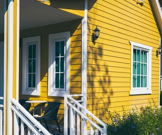 Yellow siding on a house with white trim and a white porch.