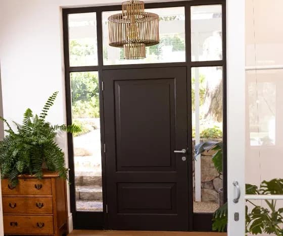 An interior view of a dark brown front door surrounded by panel windows.