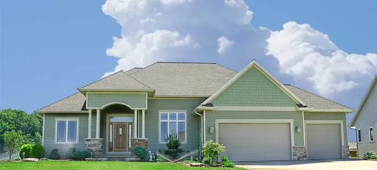 A house with light green siding and cream-colored trim with an attached two car garage.