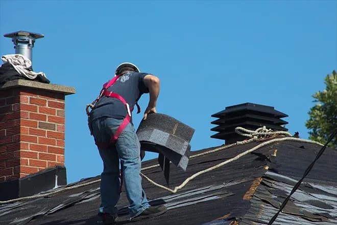 A team member on roof working to remove shingles.